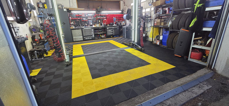 KFZ-Werkstatt mit schwarzen snapfloor Garagenboden und gelber Umrandung